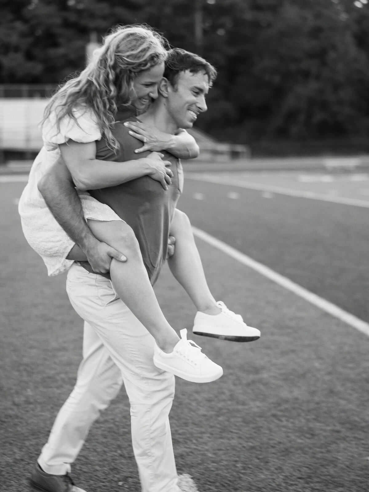 Groom carrying bride on football field photographed by Chicago editorial wedding photographer Arielle Peters