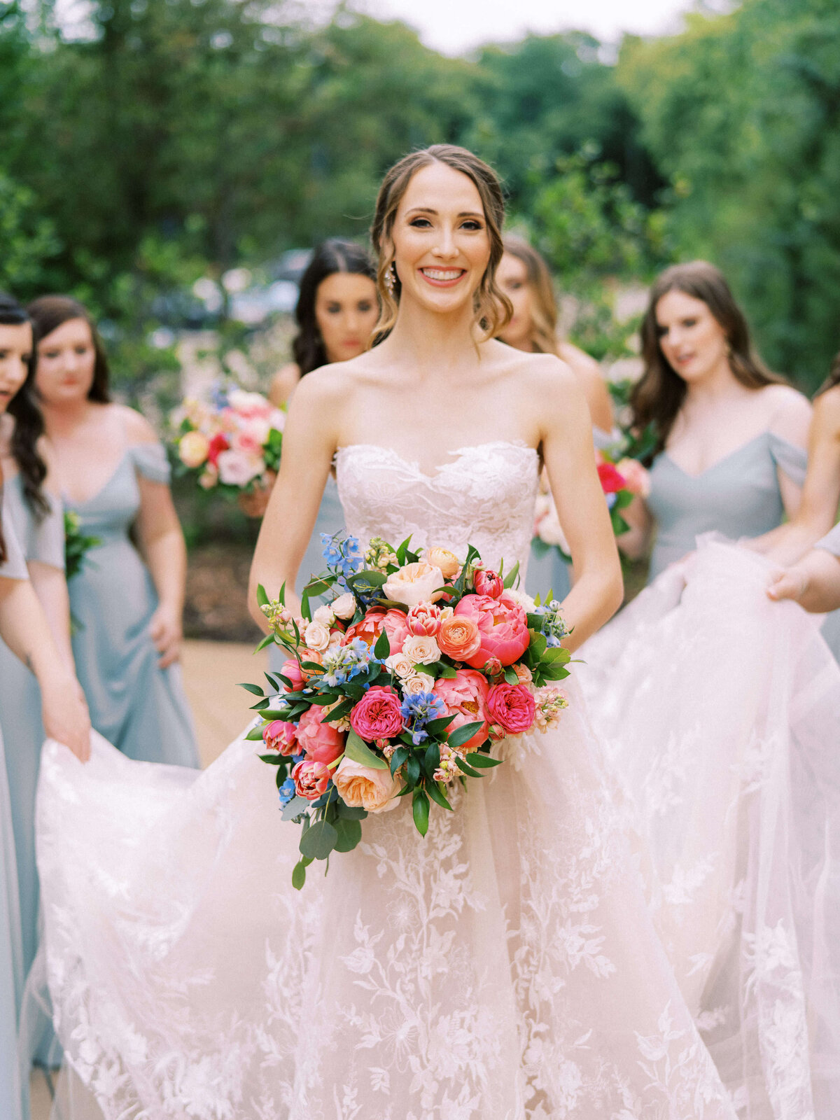 Elegant bride in Monique Lhuillier lace wedding dress holding colorful bouquet at Ashton Gardens