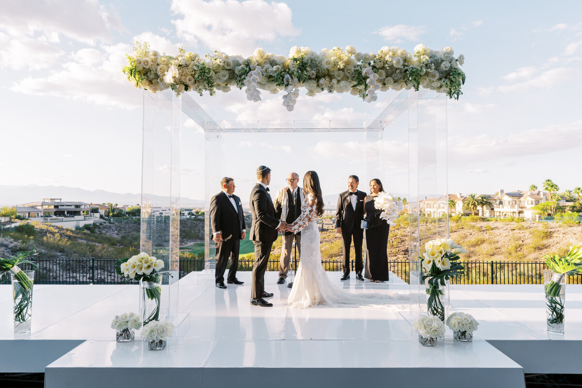 Bride and groom take their wedding vows under luxe, floral-adorned chuppah