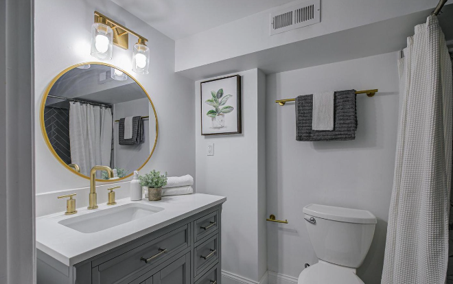 Bathroom remodel featuring a custom vanity with quartz countertop, gold fixtures, modern lighting, and stylish accents—bringing elegance and functionality into a refreshed design.