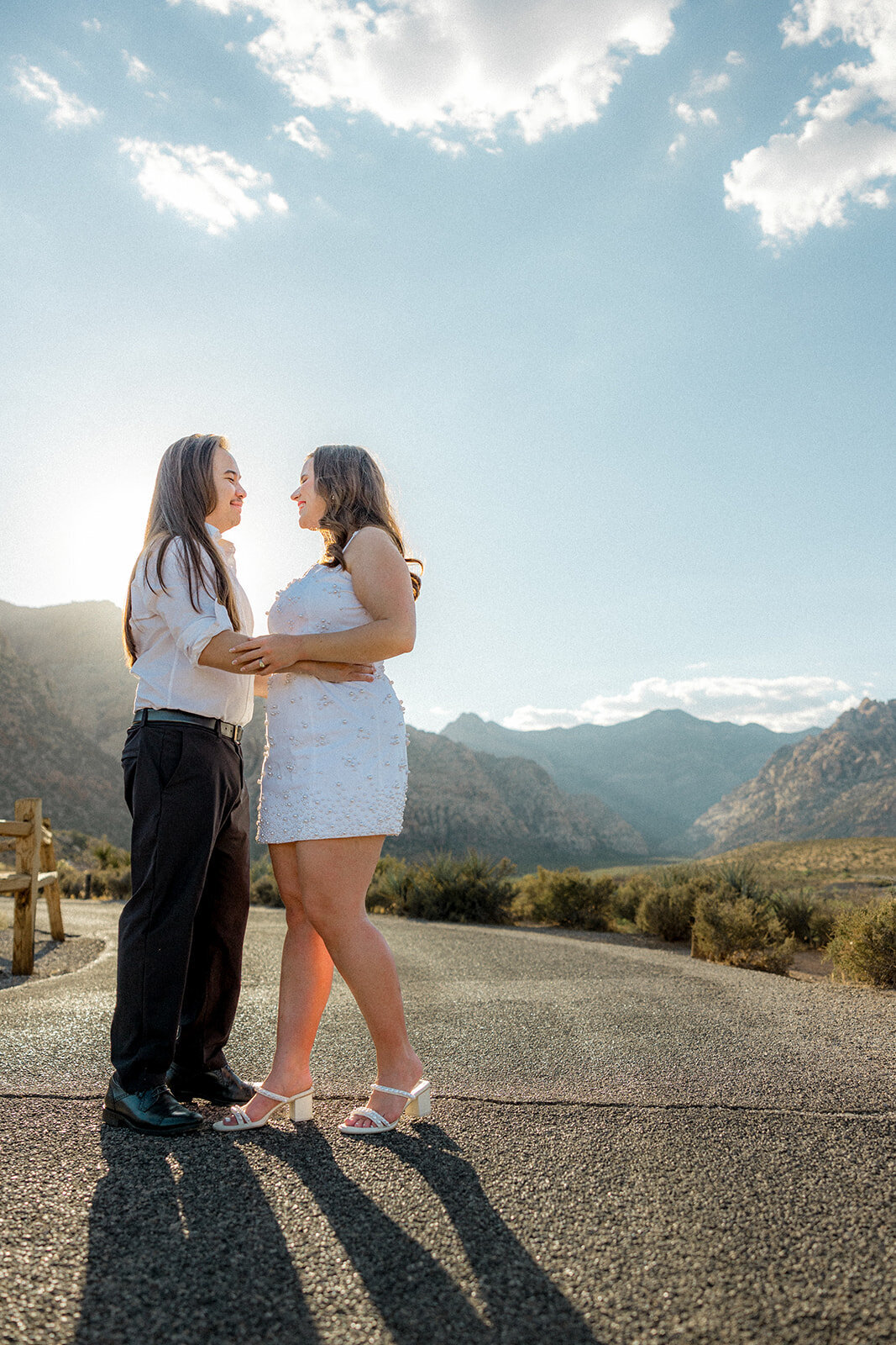 Engaged couple smiling on empty road with Nevada mountains in the back
