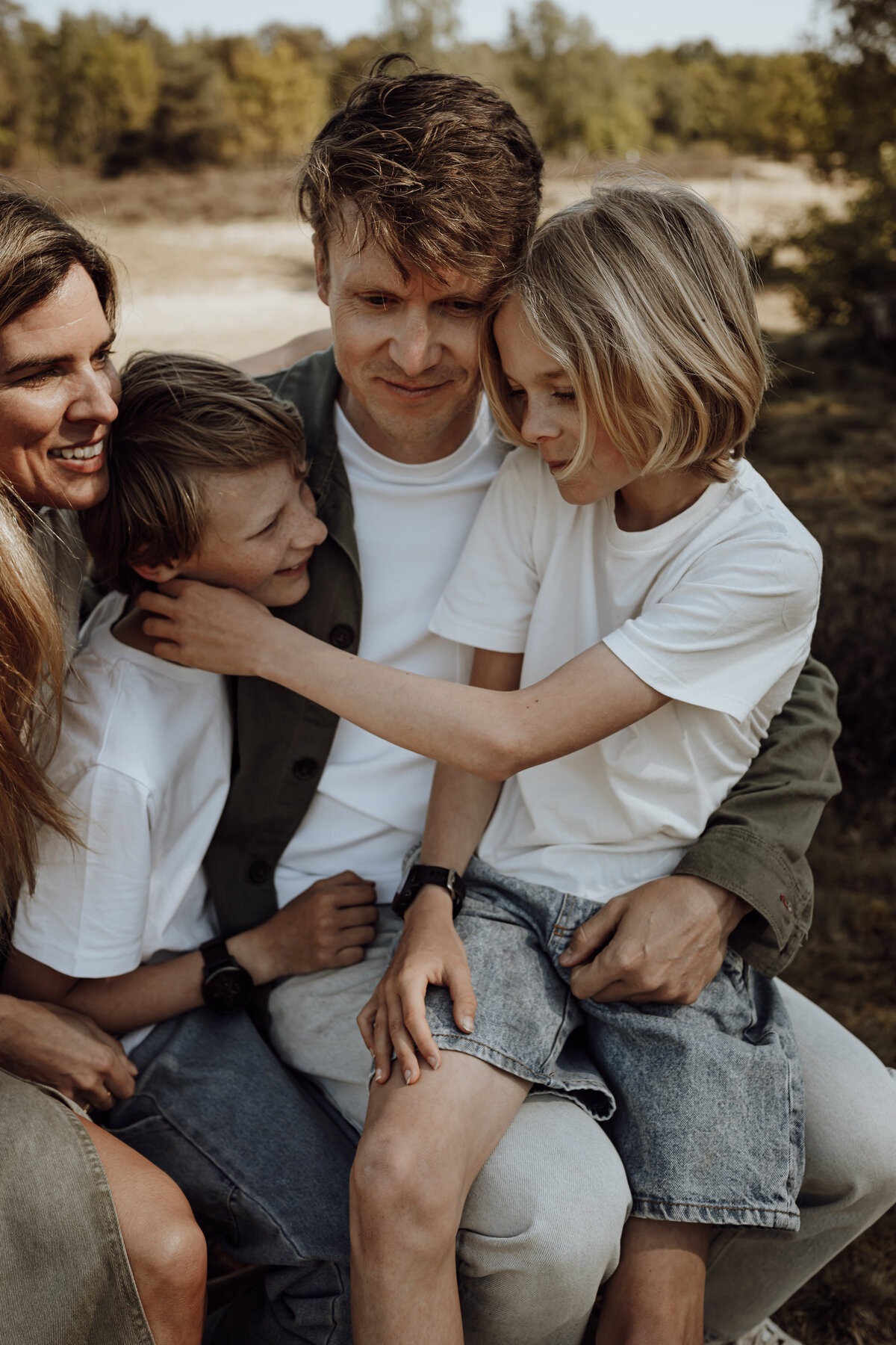 Gezin omhelst elkaar tijdens familieshoot in het bos in Antwerpen