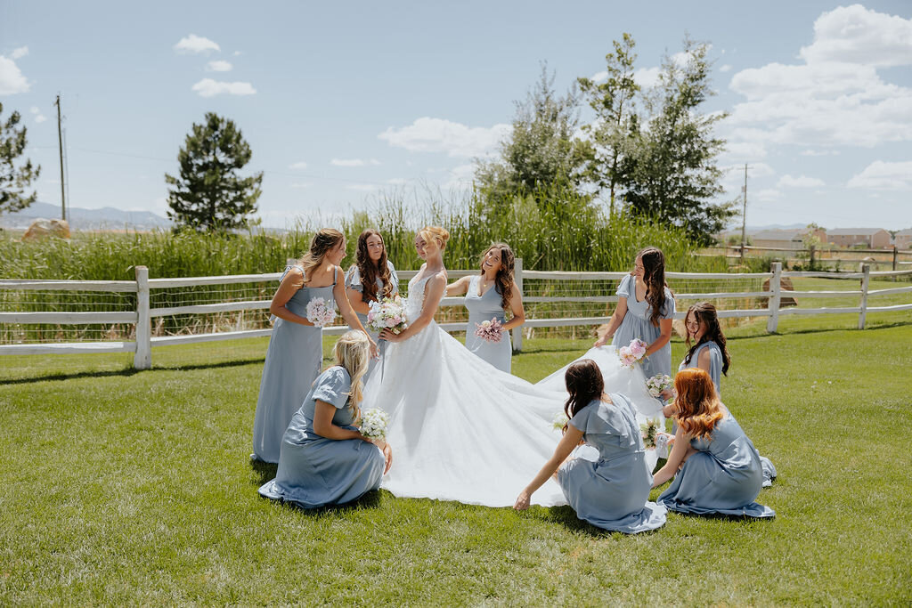 Bridesmaids arranging the bride's dress on the lawn