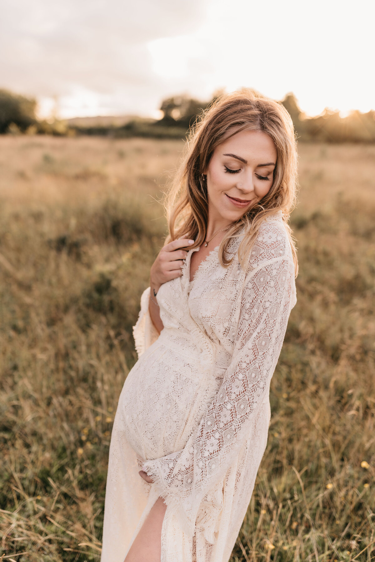Photo of a pregnant woman in a lace dress with her hands in her hair