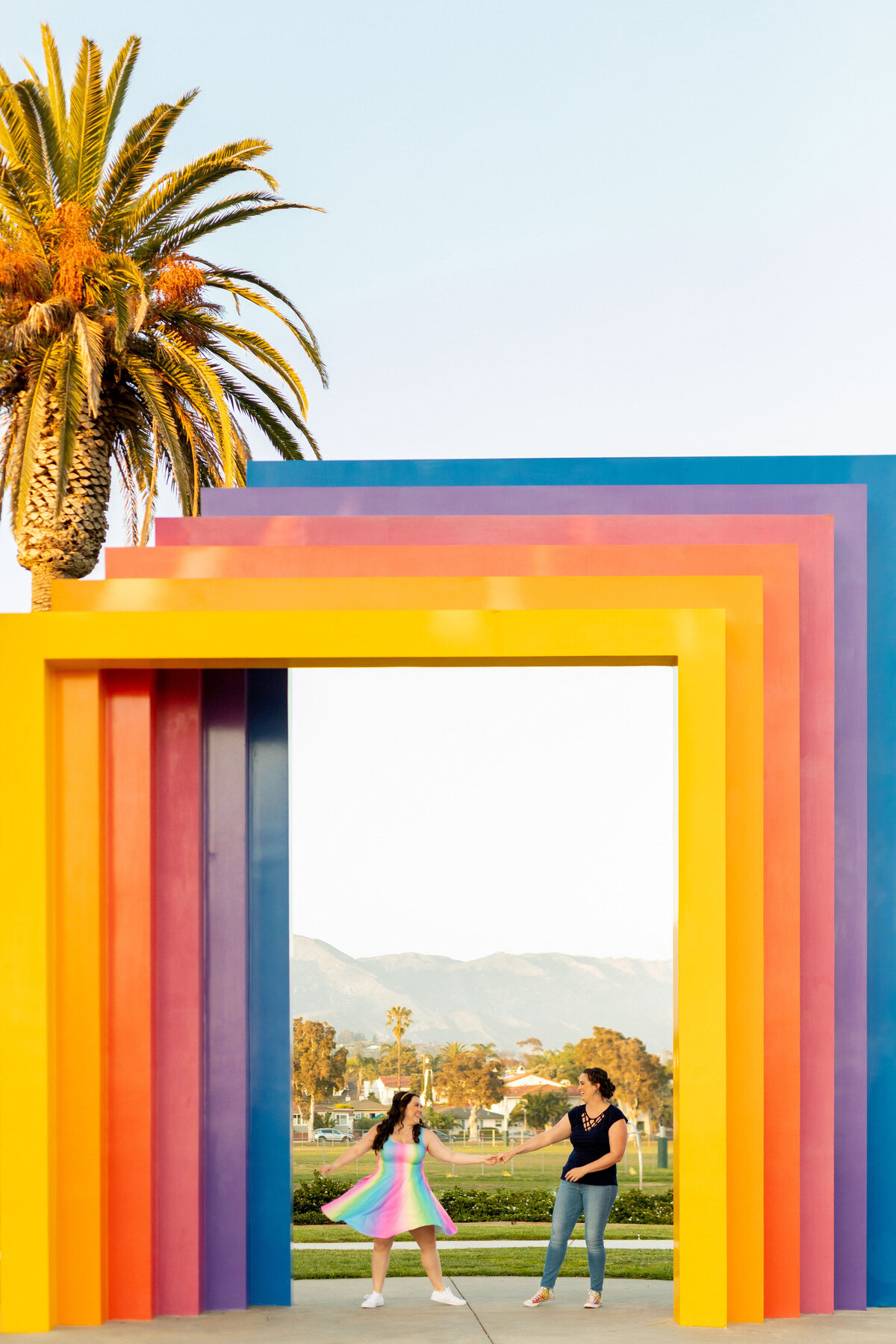 Couple dancing under a rainbow, square arch.