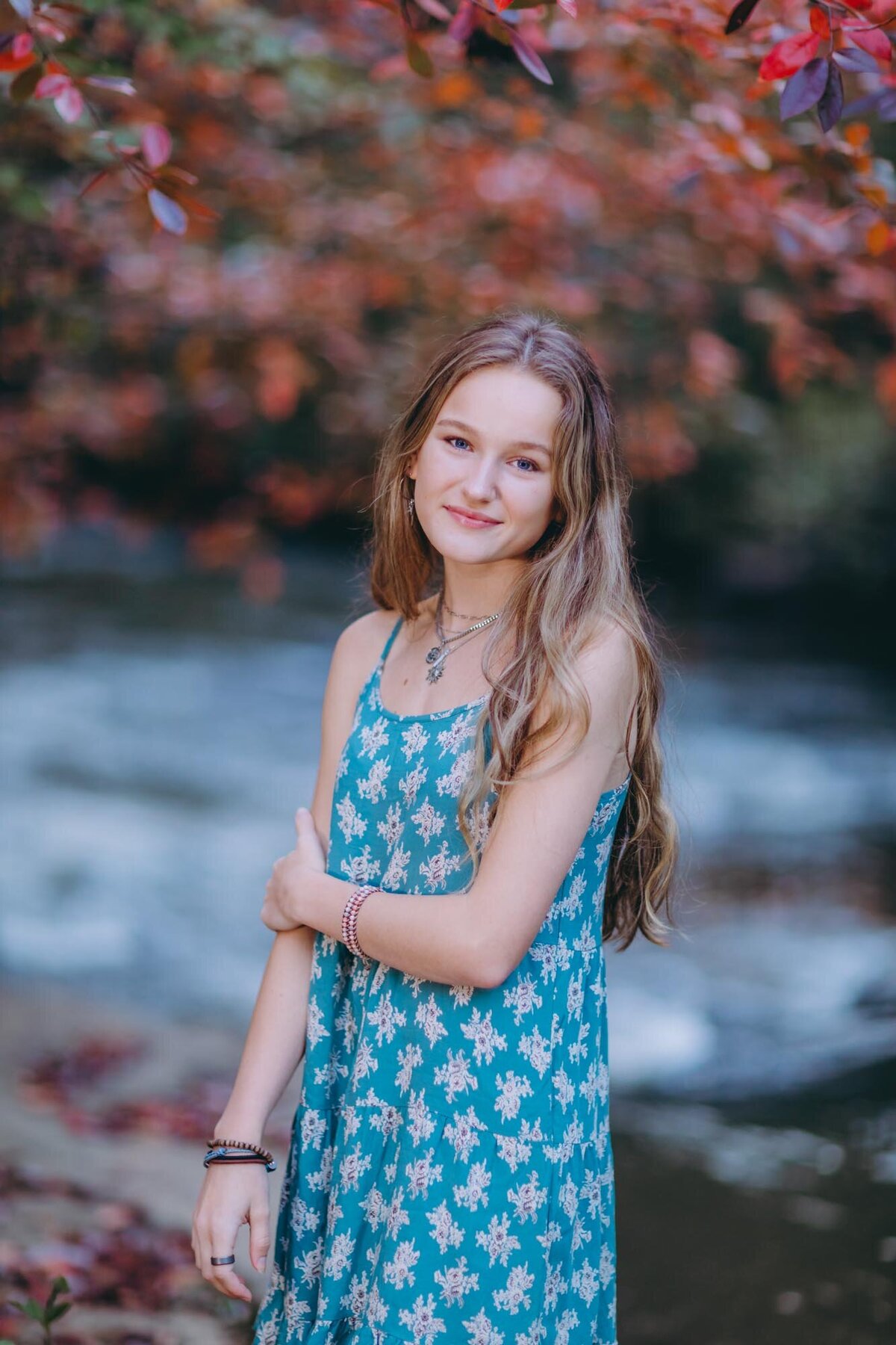 Senior girl standing under a red canopy of red leaves.