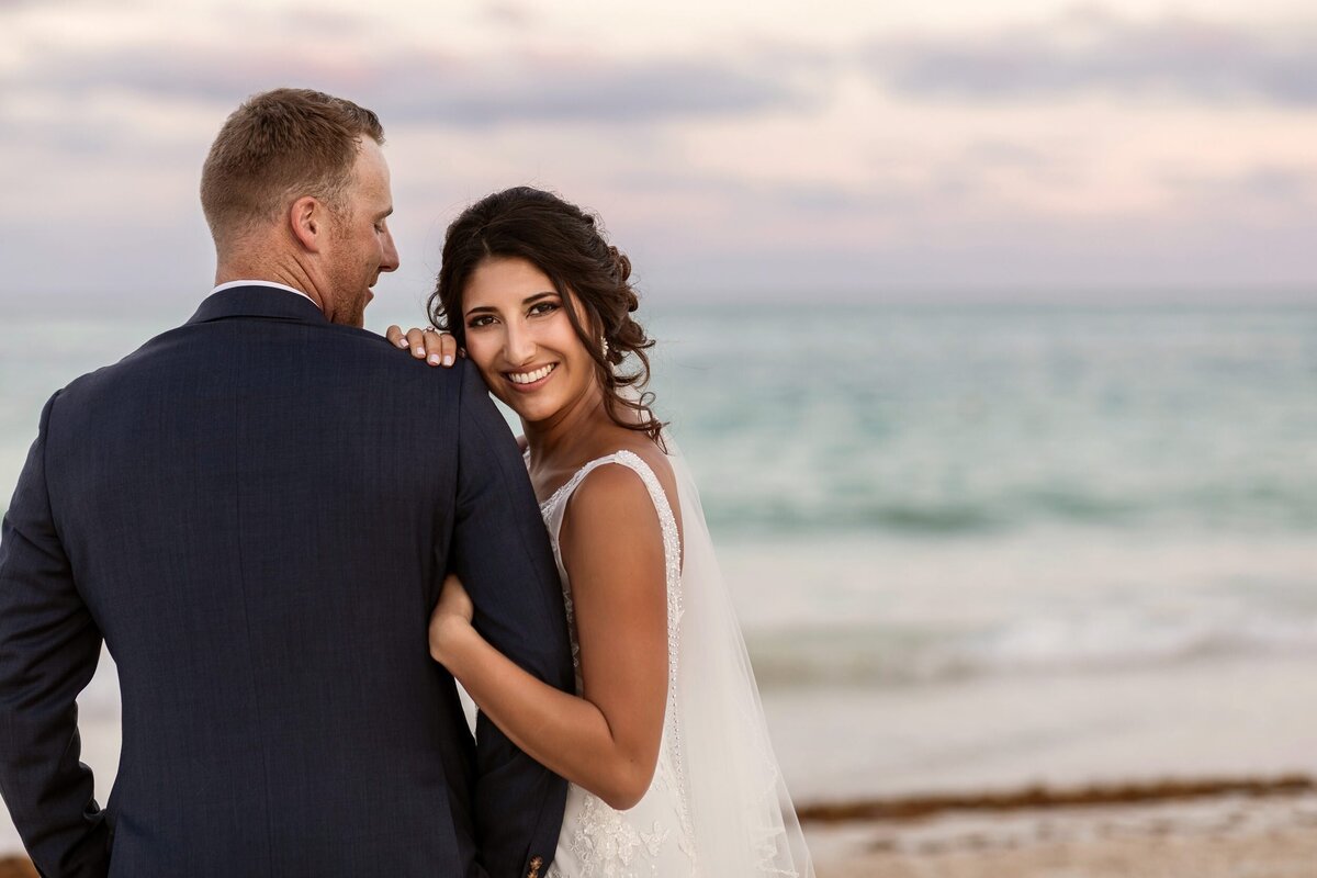 Bride hugging groom on beach at wedding at Secrets Maroma Riviera Maya