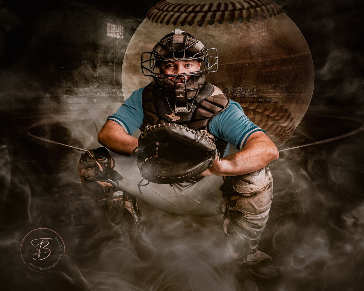 A dramatic portrait of a baseball catcher in full protective gear, including a mask, chest protector, and leg guards, crouched in a ready stance with his mitt open. A large, blurred baseball dominates the background, and a smoky or dusty effect adds to the intense atmosphere.