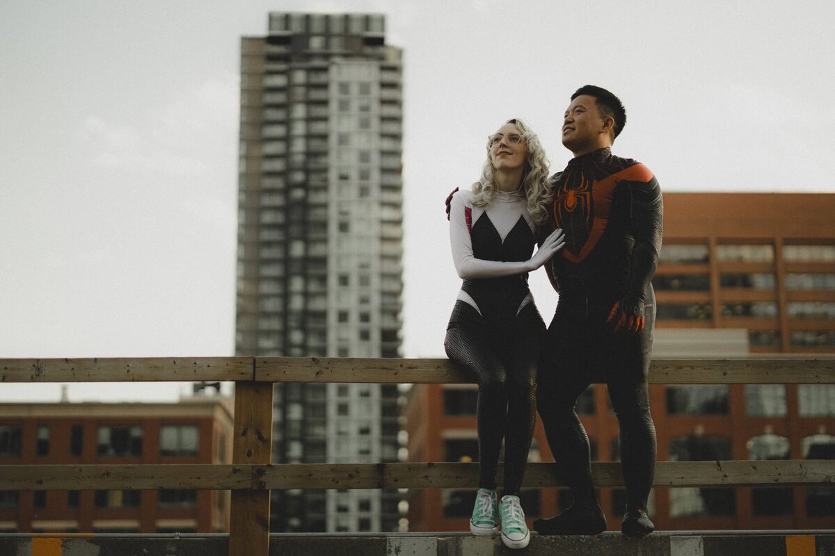 Engaged couple dress up in spiderman costumes overlooking downtown Calgary