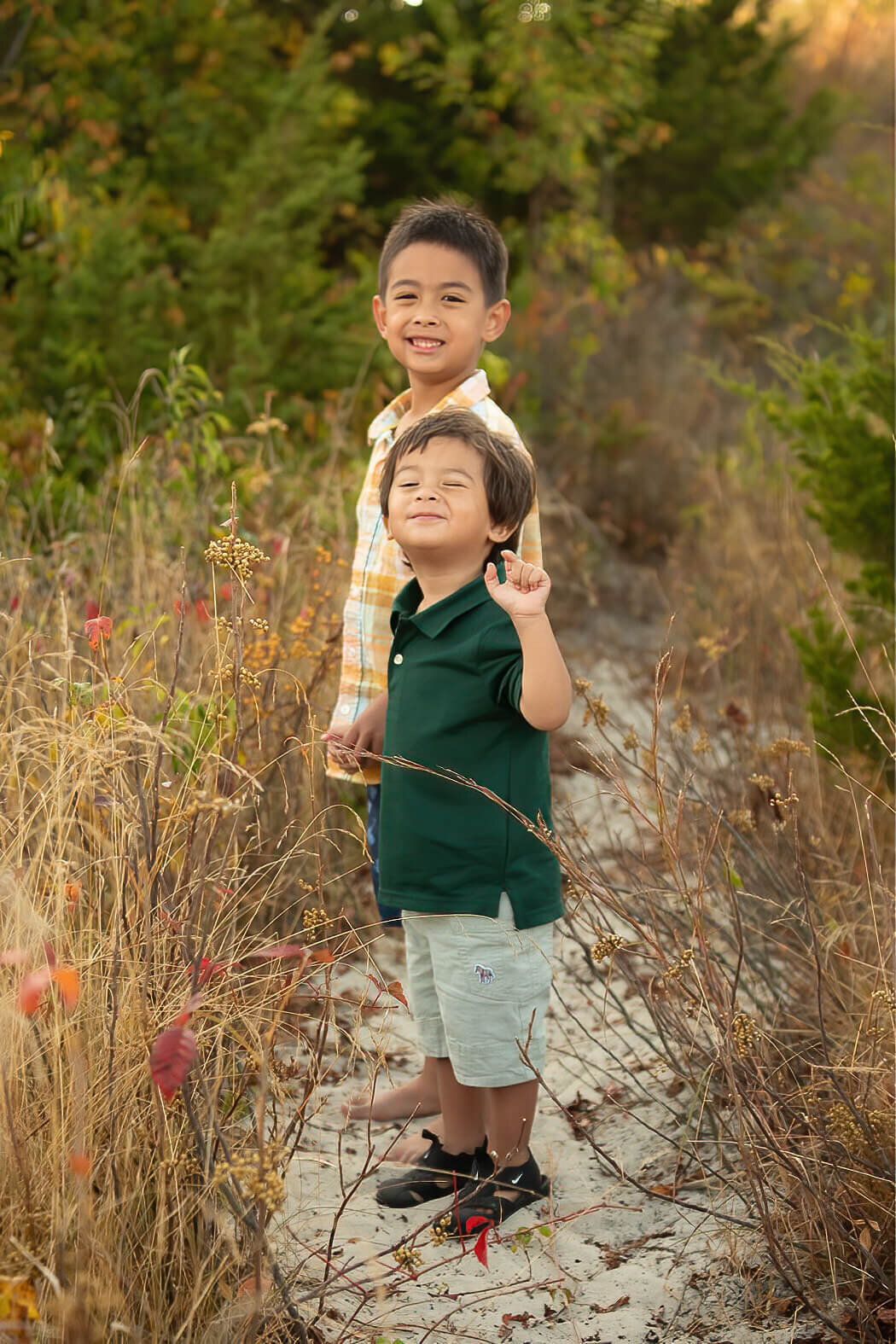 Two brothers grin at the camera as they climb a sandy bank at Wingaersheek Beach.