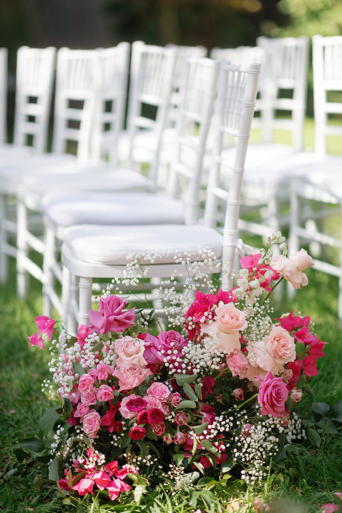 pink florals by white chairs at wedding ceremony