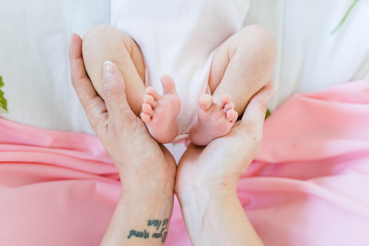 A closeup from a Northern VA photo session of a newborn baby’s feet being held by mom’s hands.