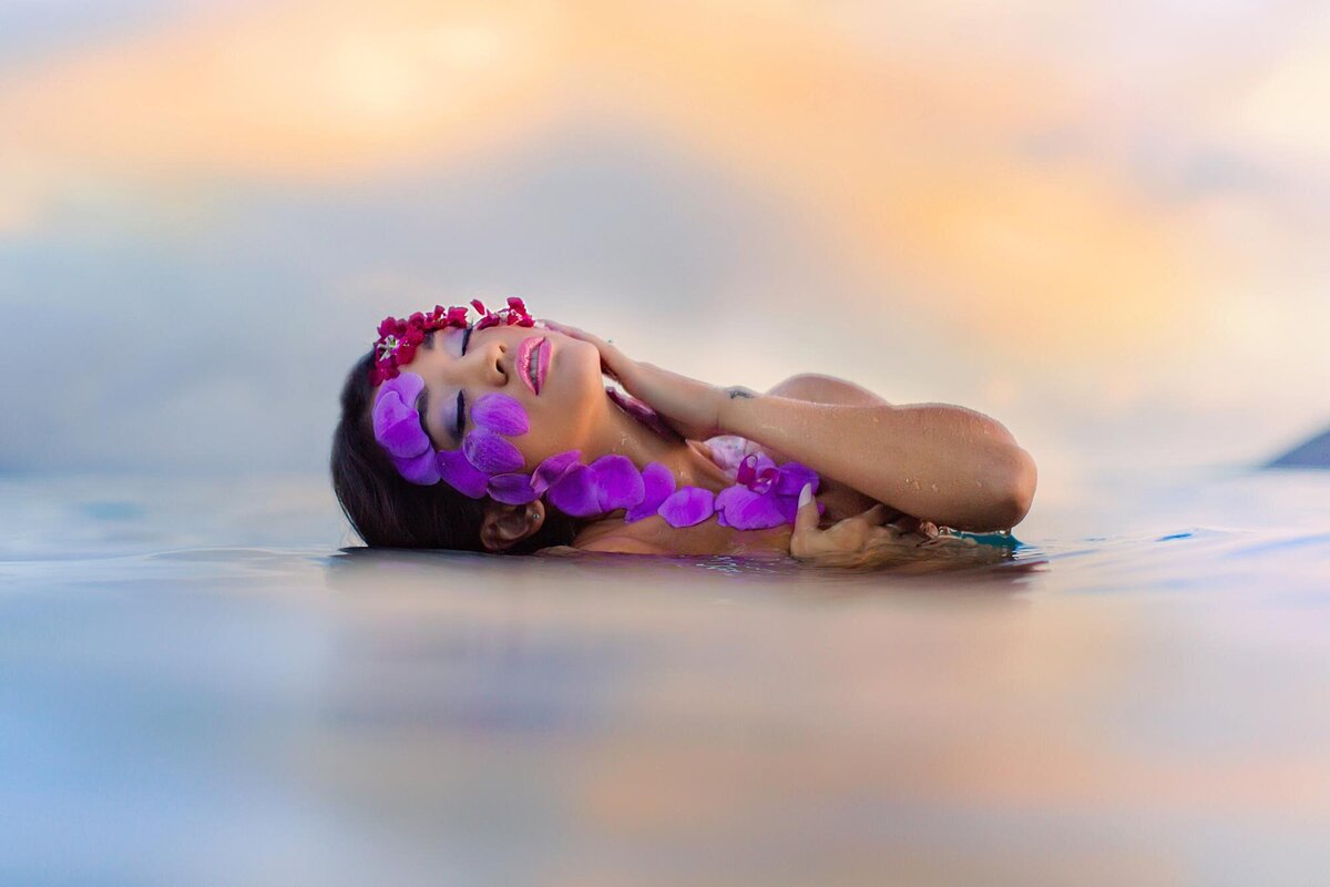 stunning portrait of a woman half-submerged in the water as she turns her face to the sky