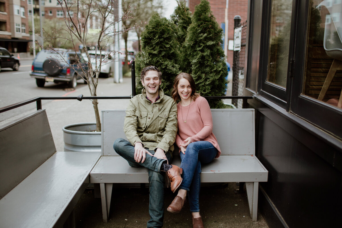 A laughing candid moment of an engaged couple sitting in an urban setting captured by Fort Worth Wedding Photographer, Megan Christine Studio