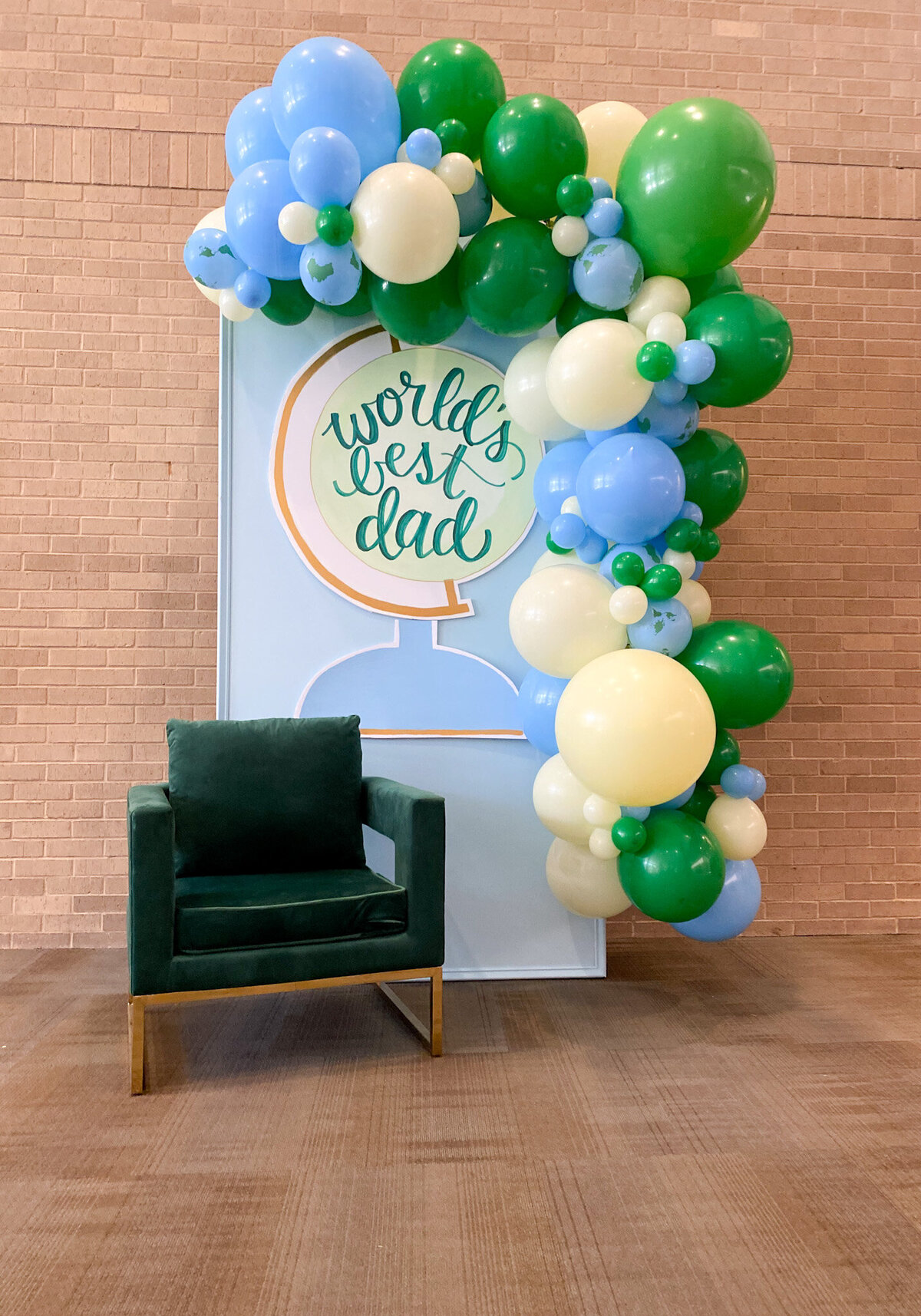 Blue and green World's Best Dad fathers day backdrop with a green chair and balloon arch