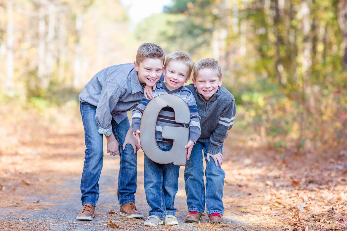 Brothers hold a giant letter G during their family portraits with Salina Korn Photography.