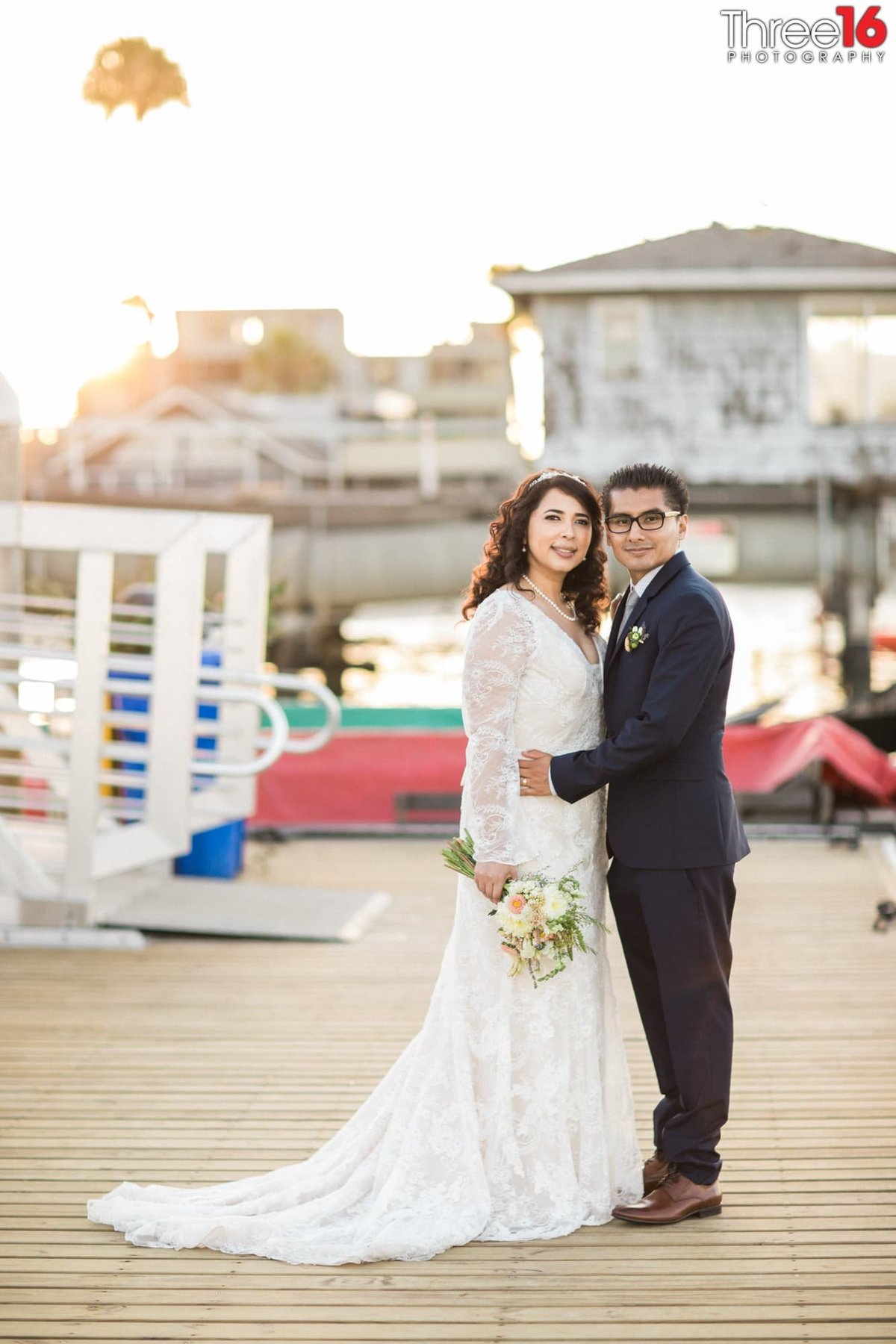 Newly married couple pose for the camera on the harbor dock