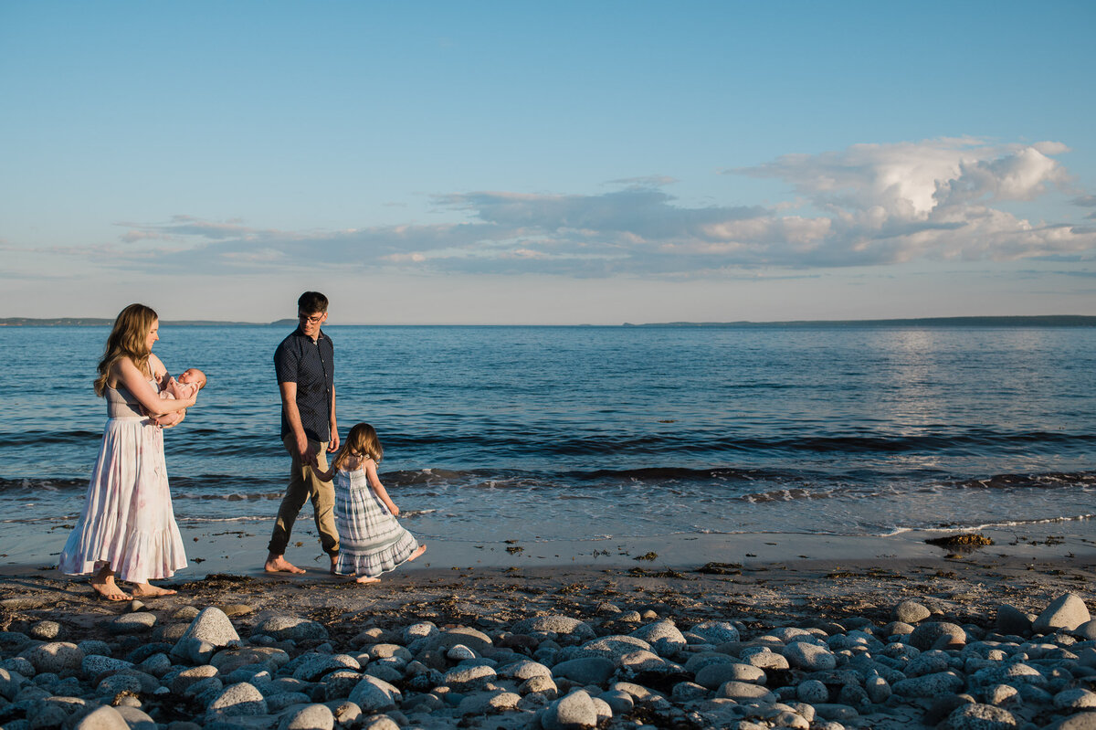 Family walking on the beach in Nova Scotia at sunset.