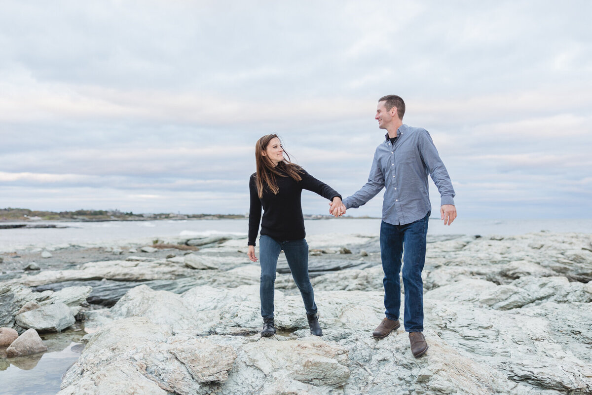 Couple walk hand in hand at Brenton Point Park during their engagement session
