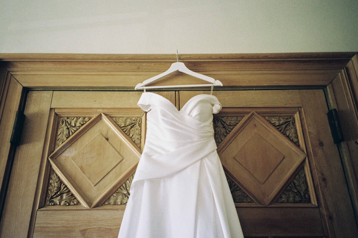 A dress is photographed hanging on a doorway.