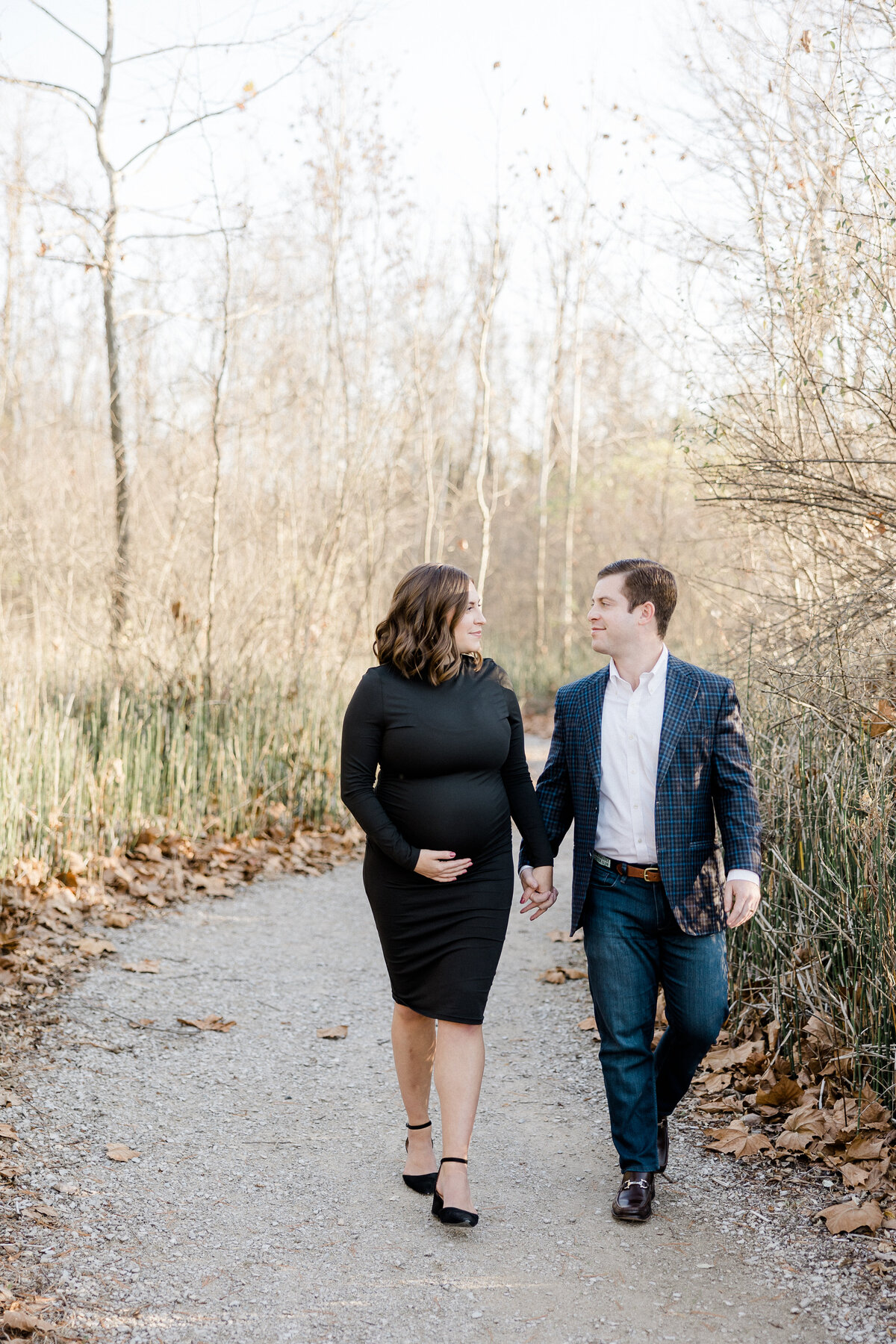 expecting parents walking down a path during maternity photos
