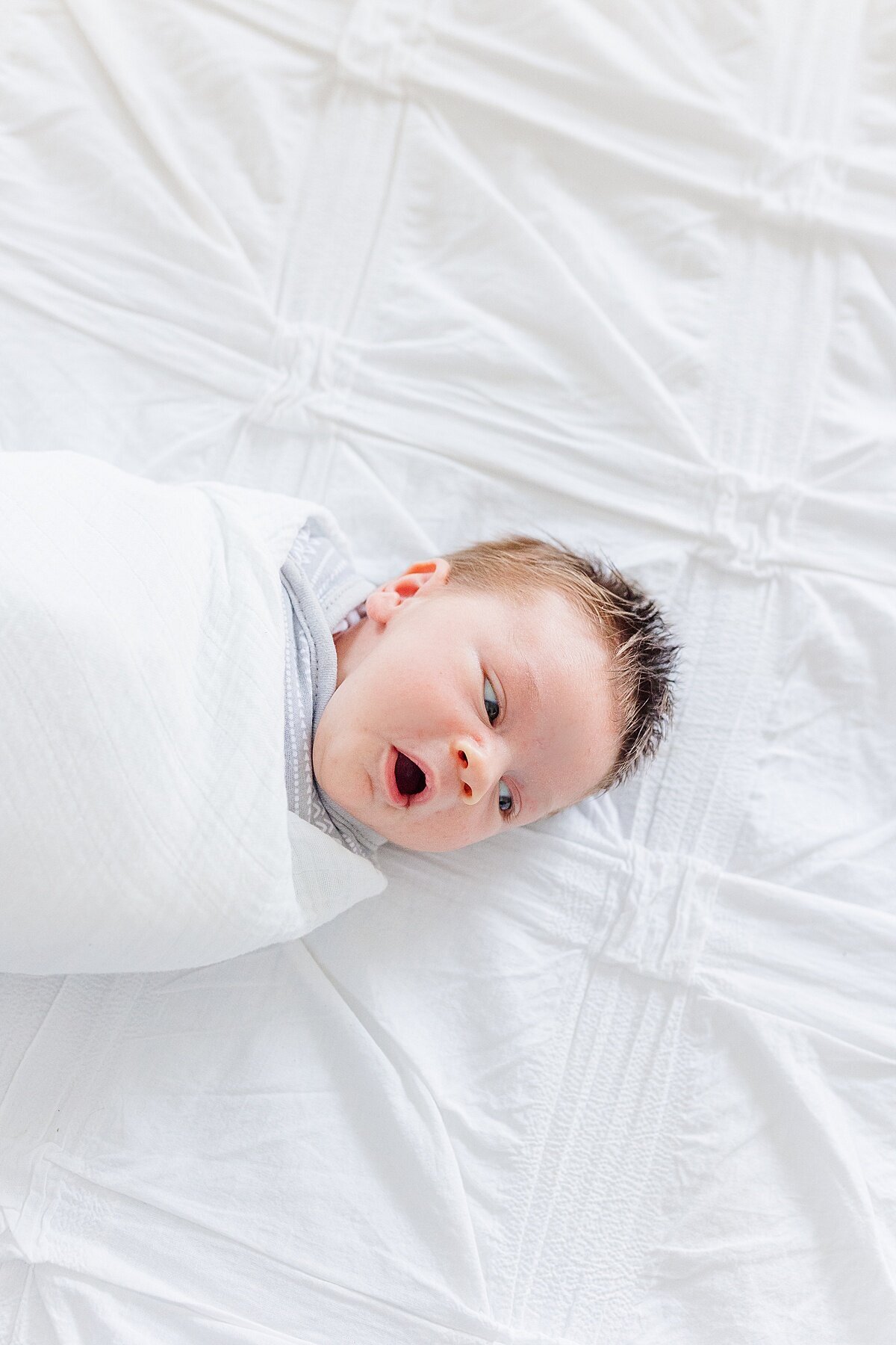 baby yawns laying on bed during in home newborn photo session with Sara Sniderman Photography  in Natick Massachusetts