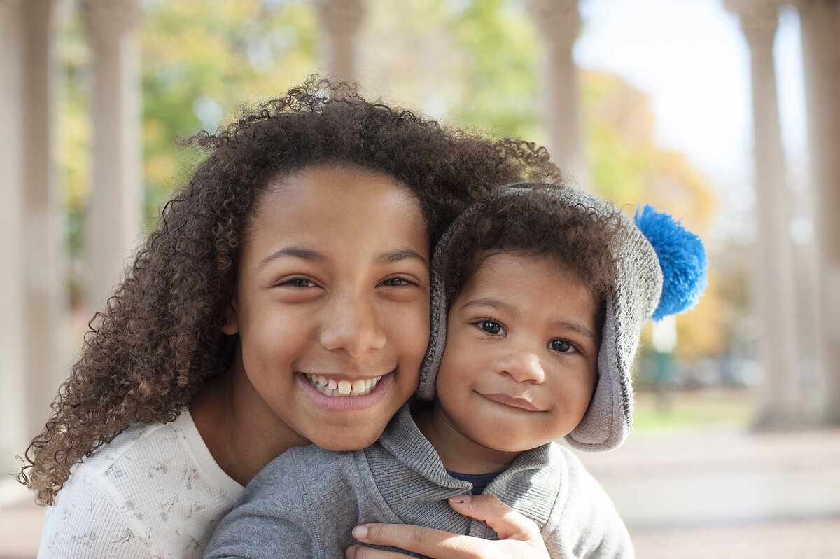 Two siblings hug as they both smile 