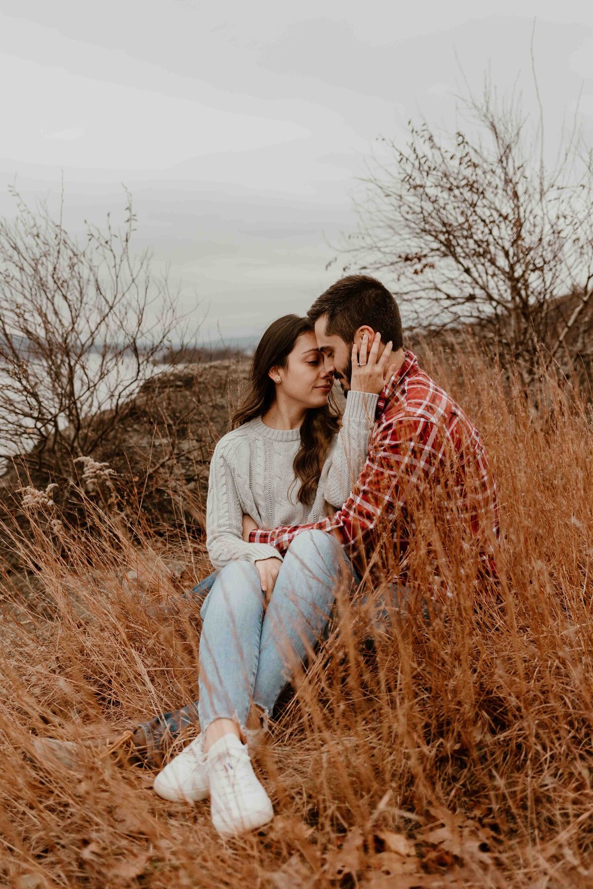 Engaged couple sitting in grass