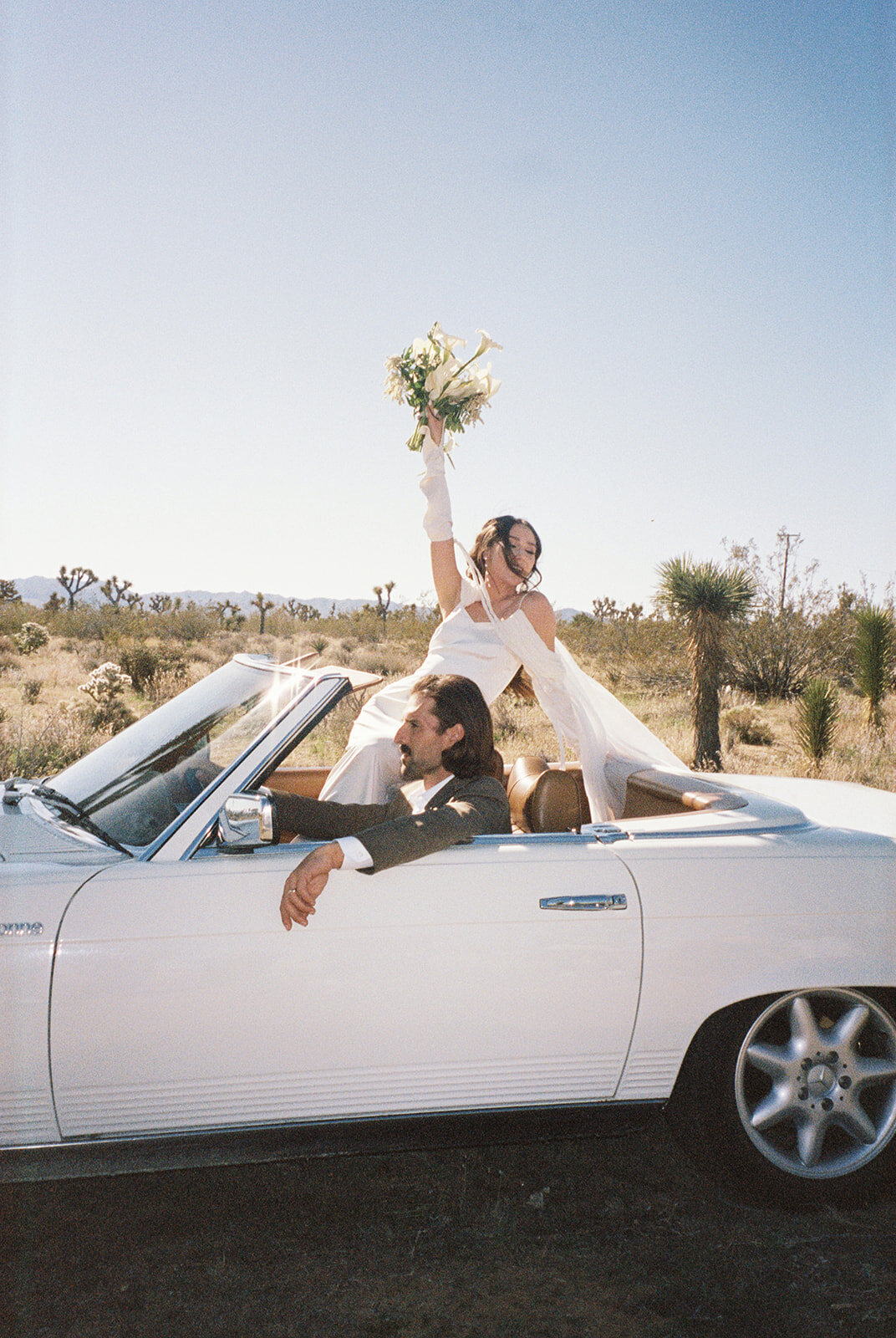 west coast wedding photography of couple driving through desert in vintage car