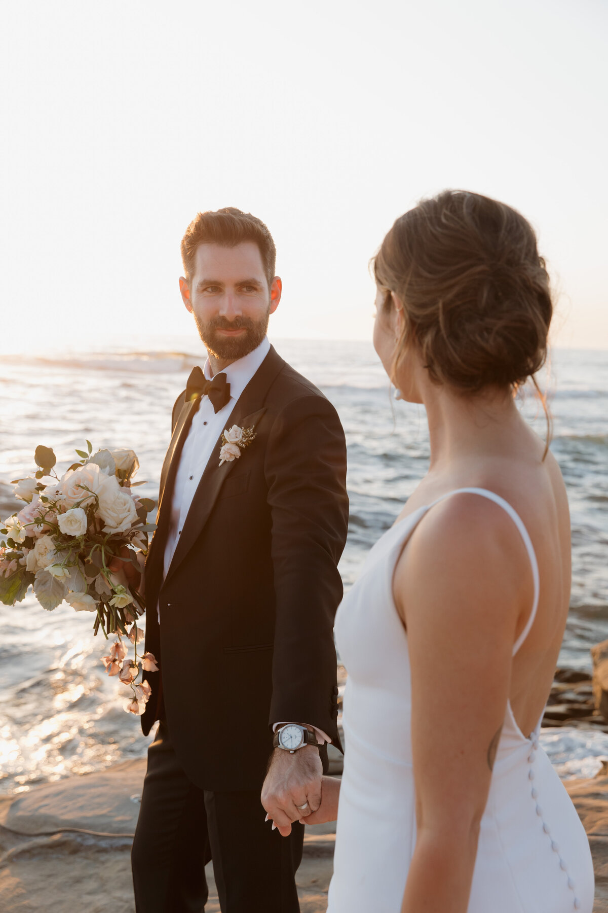 Bride and groom sharing an intimate moment at sunset on the San Diego coast, captured in a fine art wedding photography style.