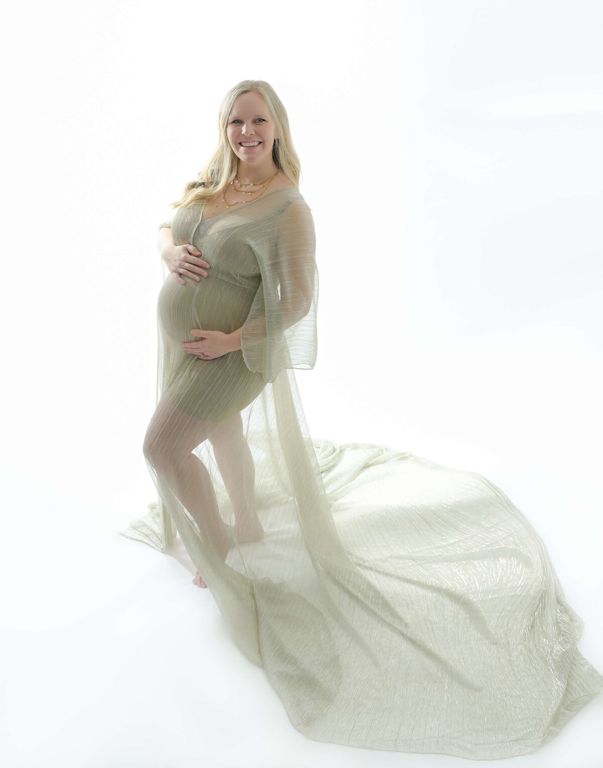 Beth Benecki photographs this backlit maternity session with the mother wearing a gold flowing sheer dress that highlights the growing belly.