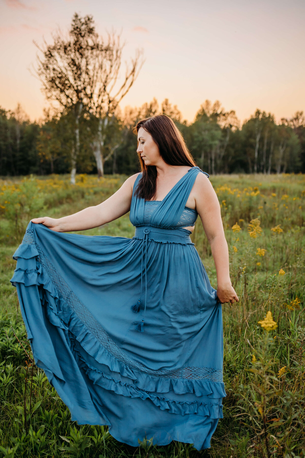 mom twirling blue dress in field during sunset