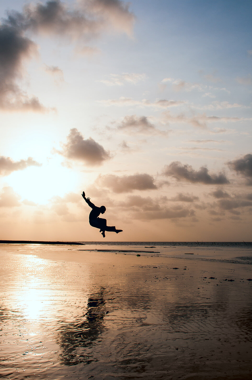 A person jumping up in a pose at the water's edge