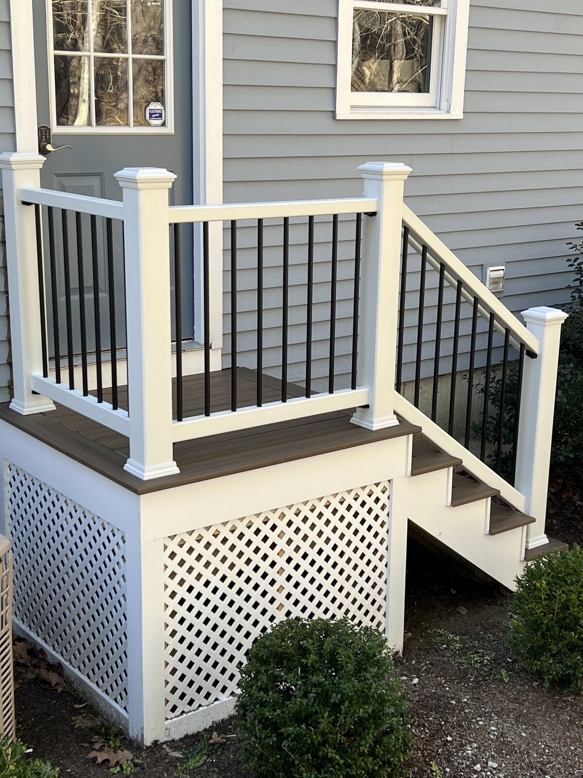 A small deck with stairs and PVC trellis and railing
