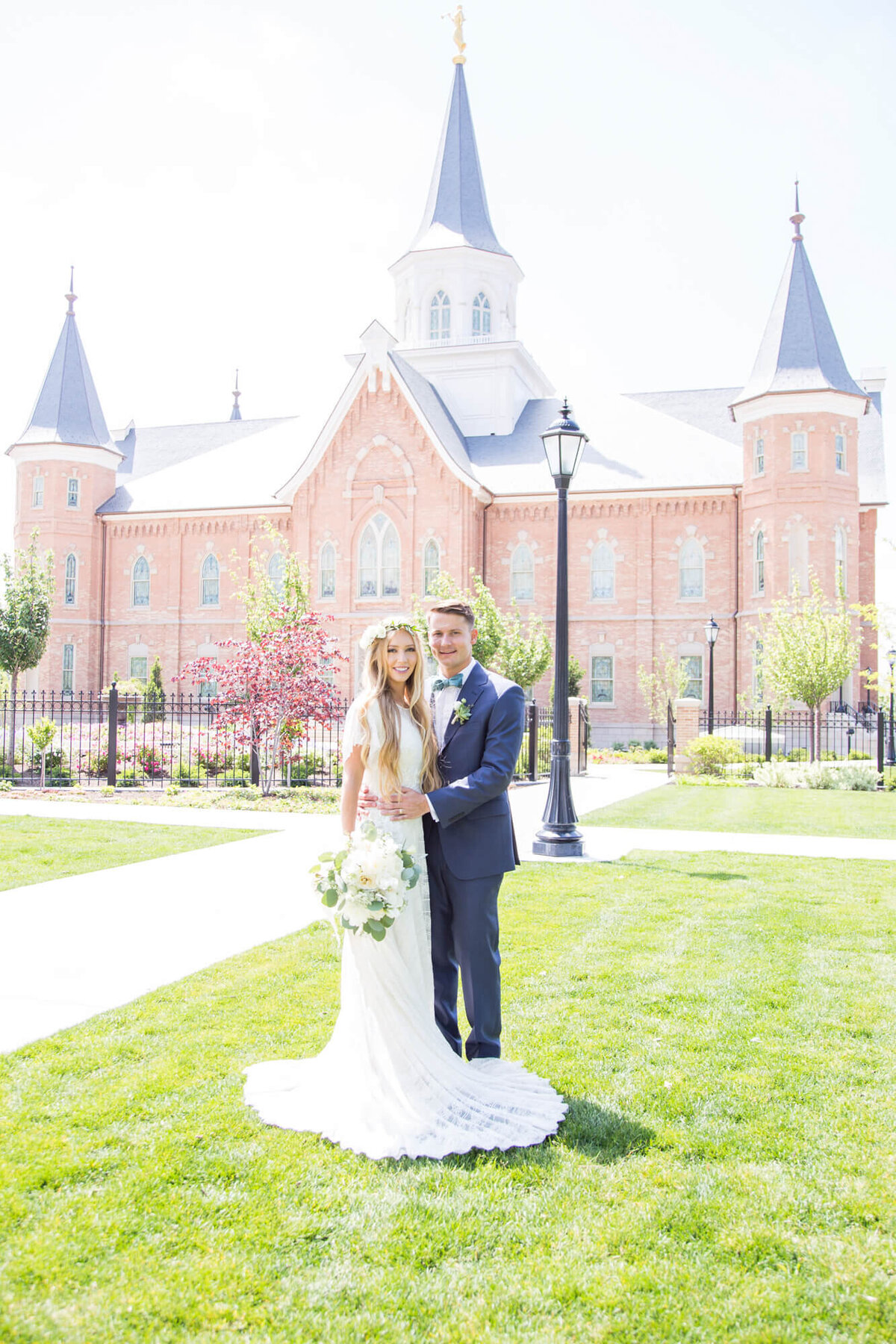 wedding couple standing on grass in front of the provo city center temple