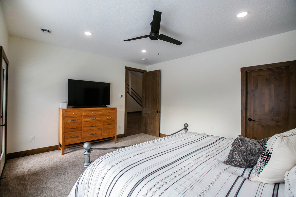 Spacious primary bedroom in custom Otsego home with natural light and dark wood accents