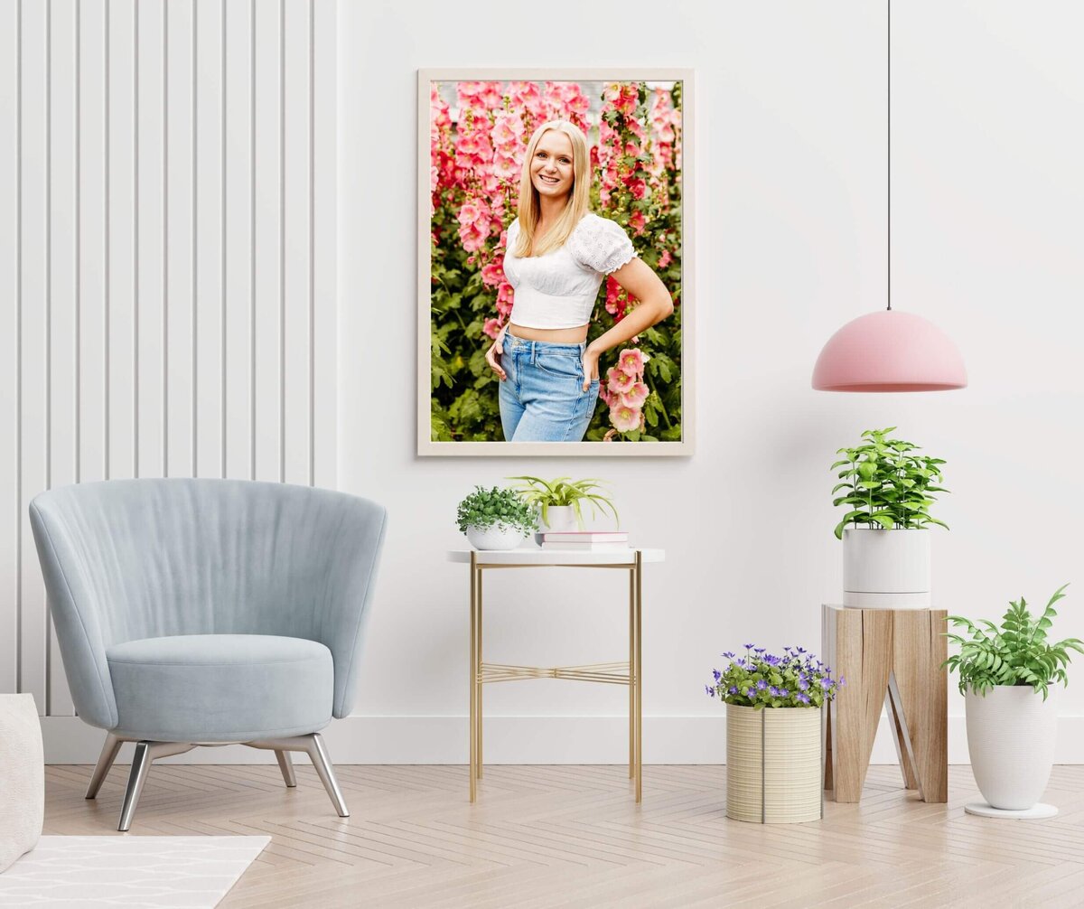 portrait of a high school girl and pink flowers hanging in a living area with white walls and modern accents