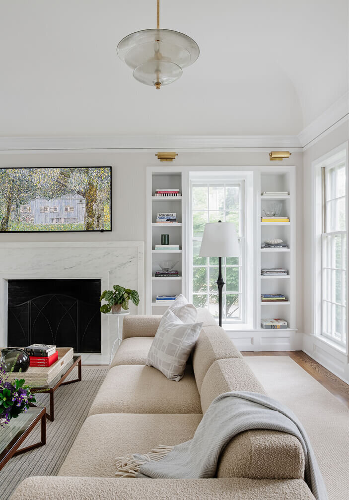 Scandinavian sofa in a historic home living room in Hingham, designed by interior designers in Boston, blending minimalist style with classic architecture.