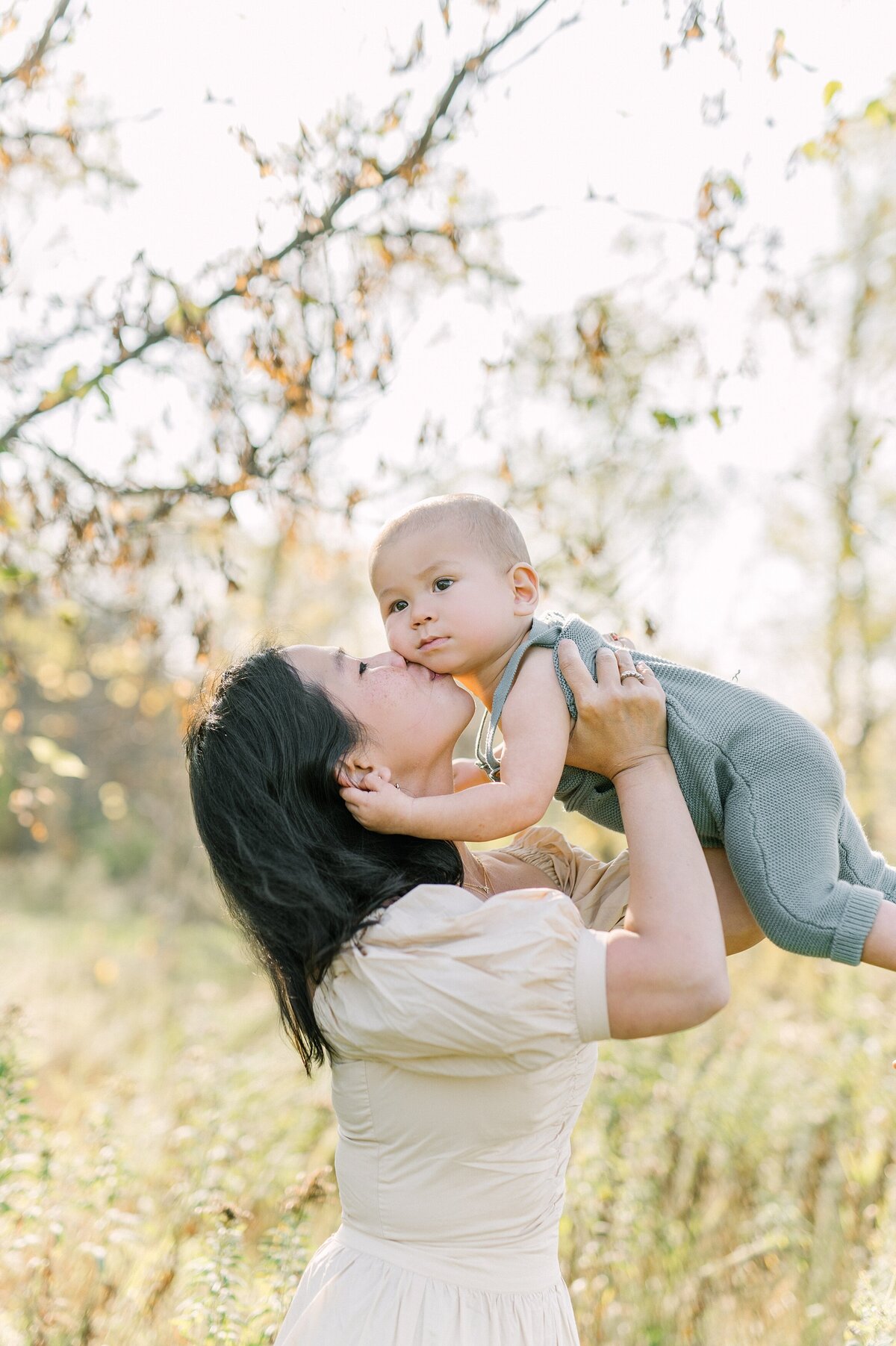 mom lifting her one year old son in the air