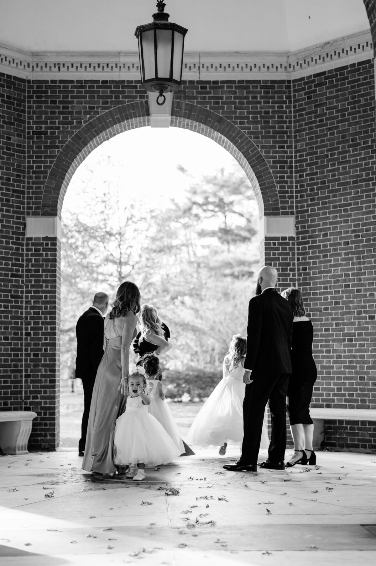 Bridal party stands outside underneath a Washington DC arch