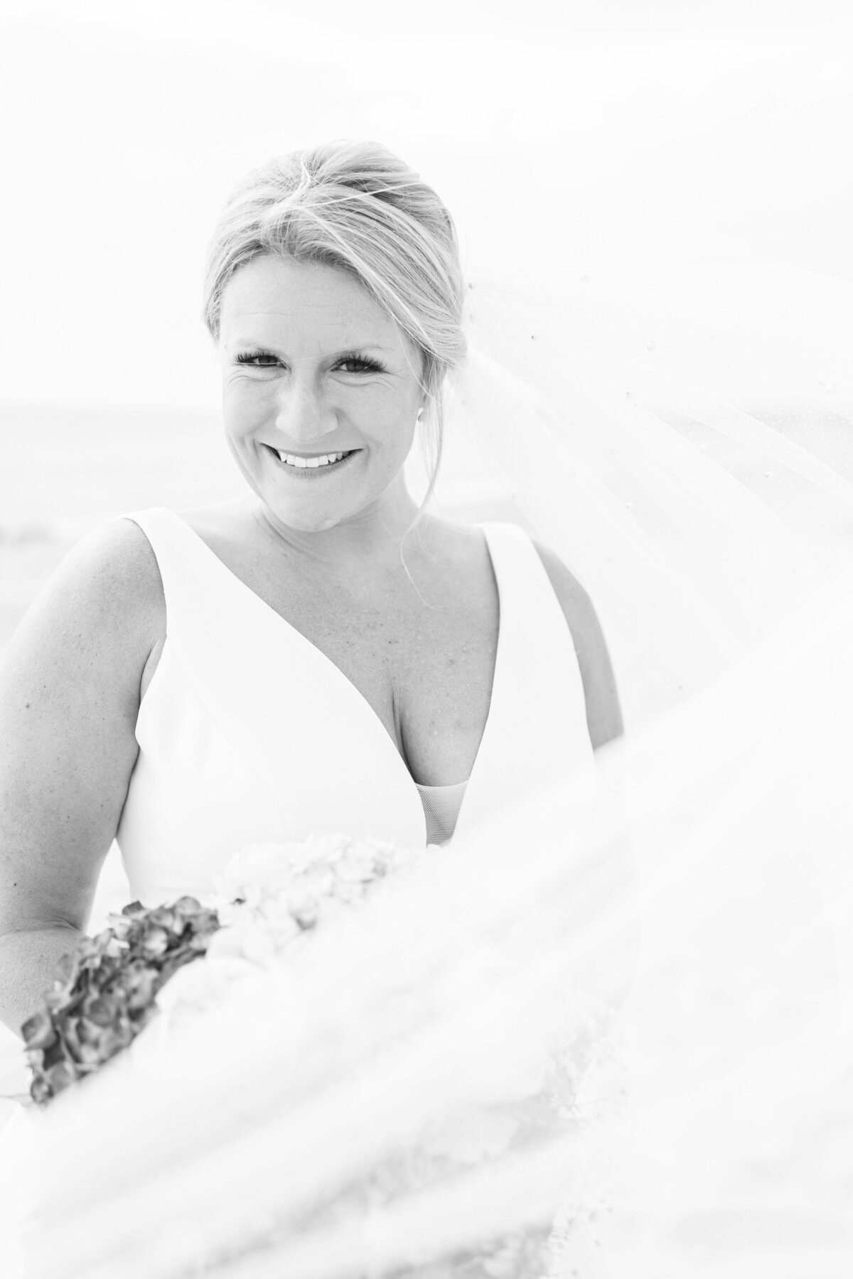 Black and white photo of a bride smiling at the camera representing romantic Cape Cod wedding pictures
