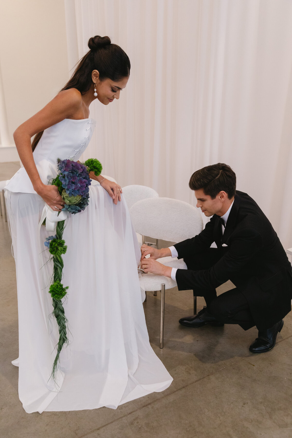 Bride and groom sharing an intimate moment in a white, draped ceremony space.