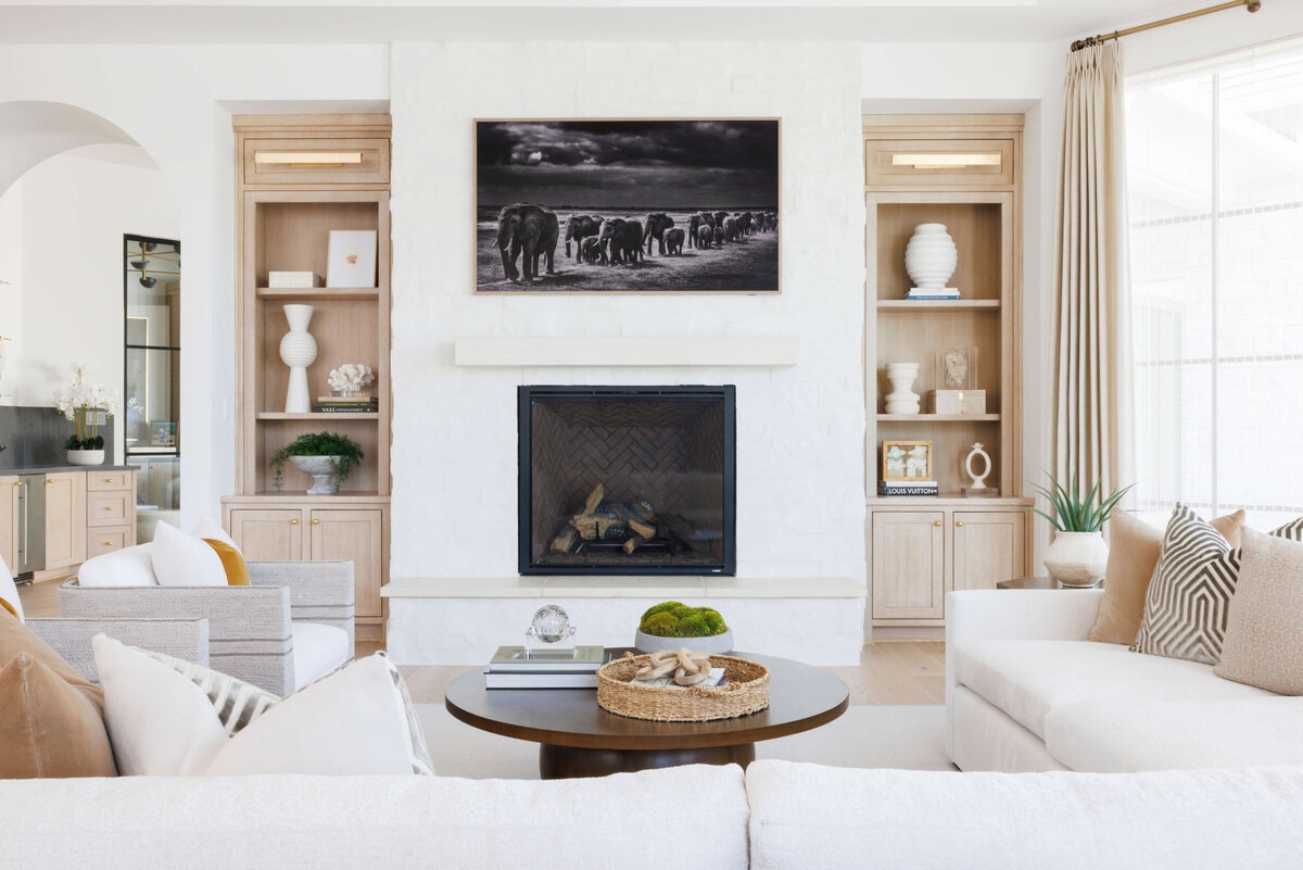 oyster creek studios hughes white sofa and dark wooden coffee table around a white fireplace in living room