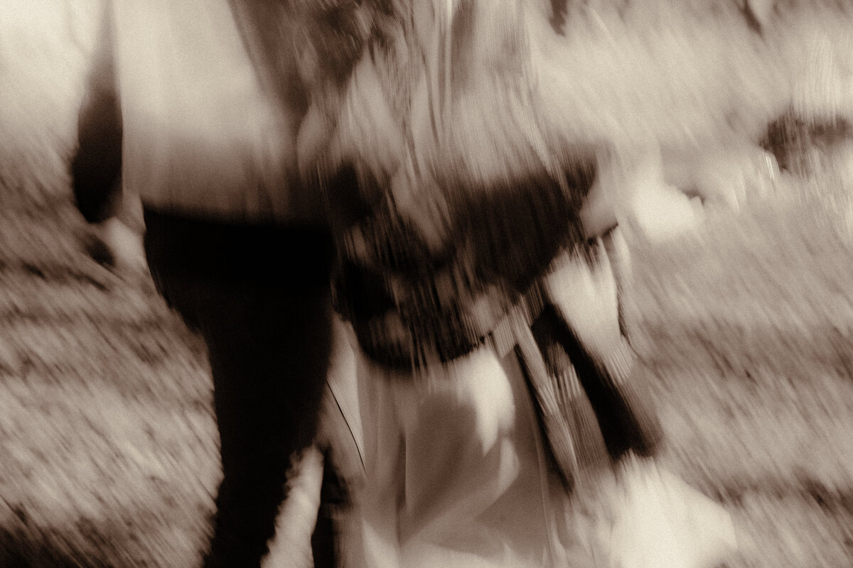 Slow shutter of a cowboy elopement couple walking through a field.