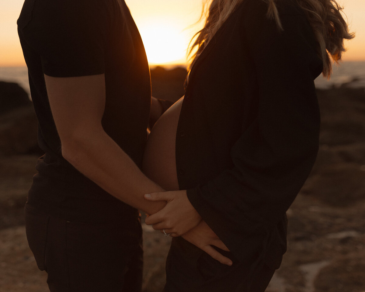 mama to be holding an ultrasound photo with husband against belly