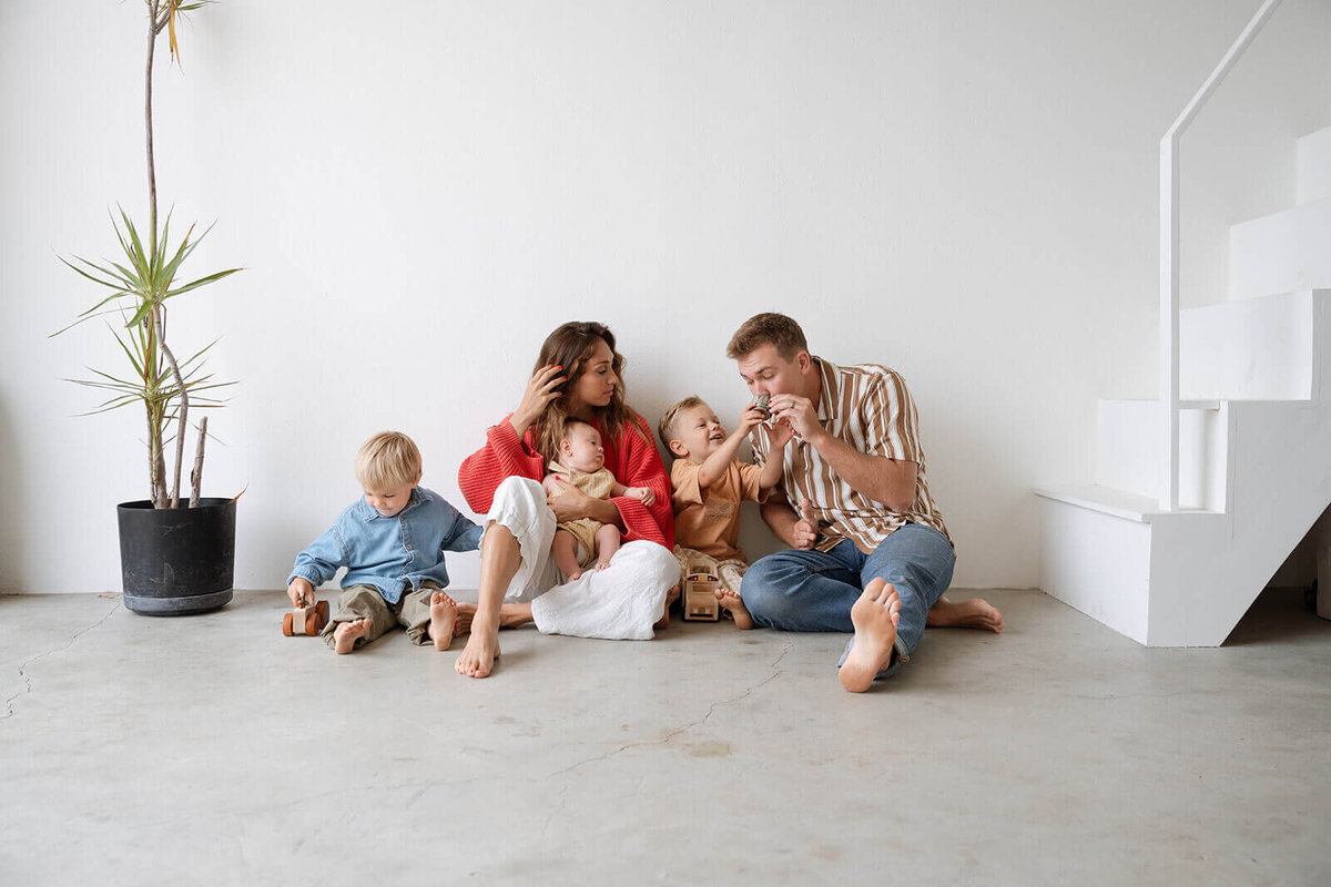 mother and father sitting on floor with two boys and baby in costa mesa studio