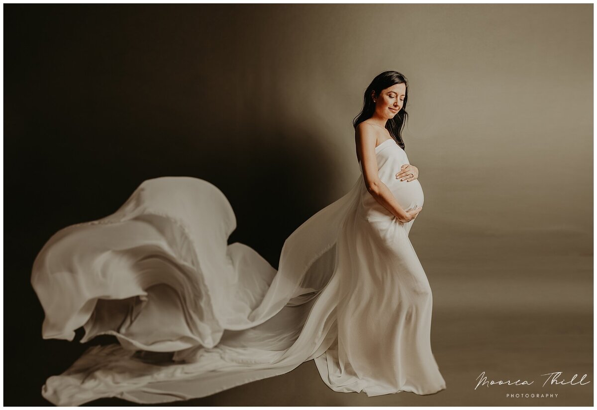 expecting mother holding her bump during a fine art studio session with moorea thill