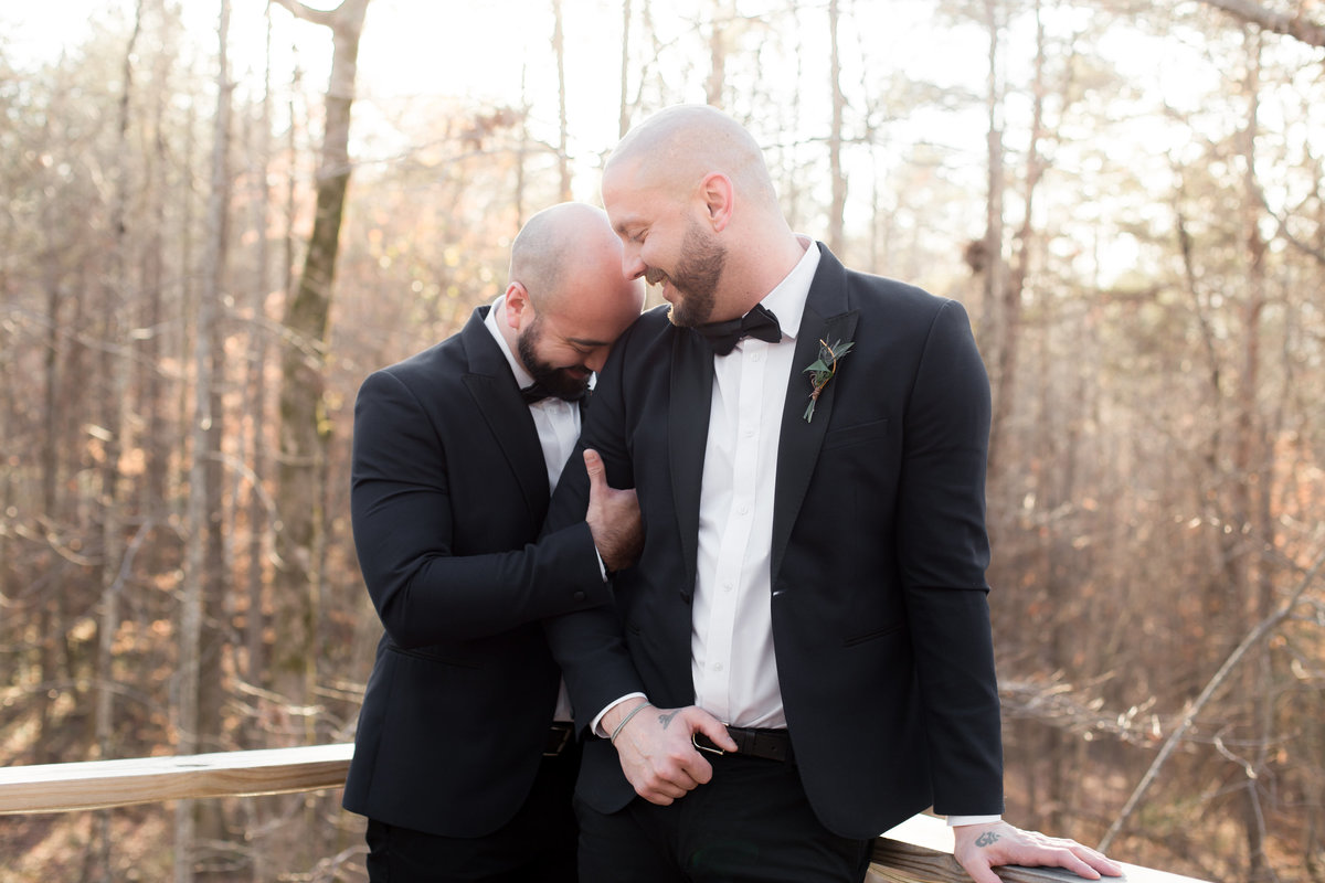 gay couple poses outdoor at treehouse for wedding photographer