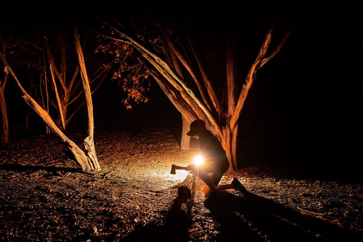 A young boy hacks wood while camping. 