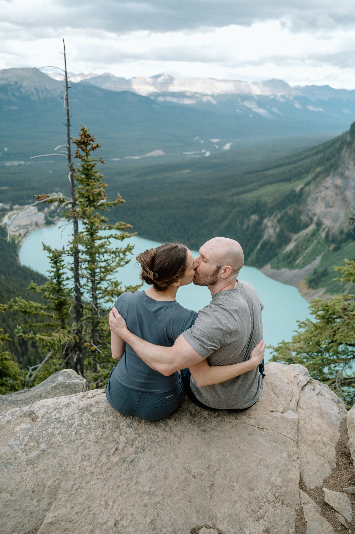 Couple kiss with mountain backdrop at big beehive hike, captured during a stunning mountain proposal session.